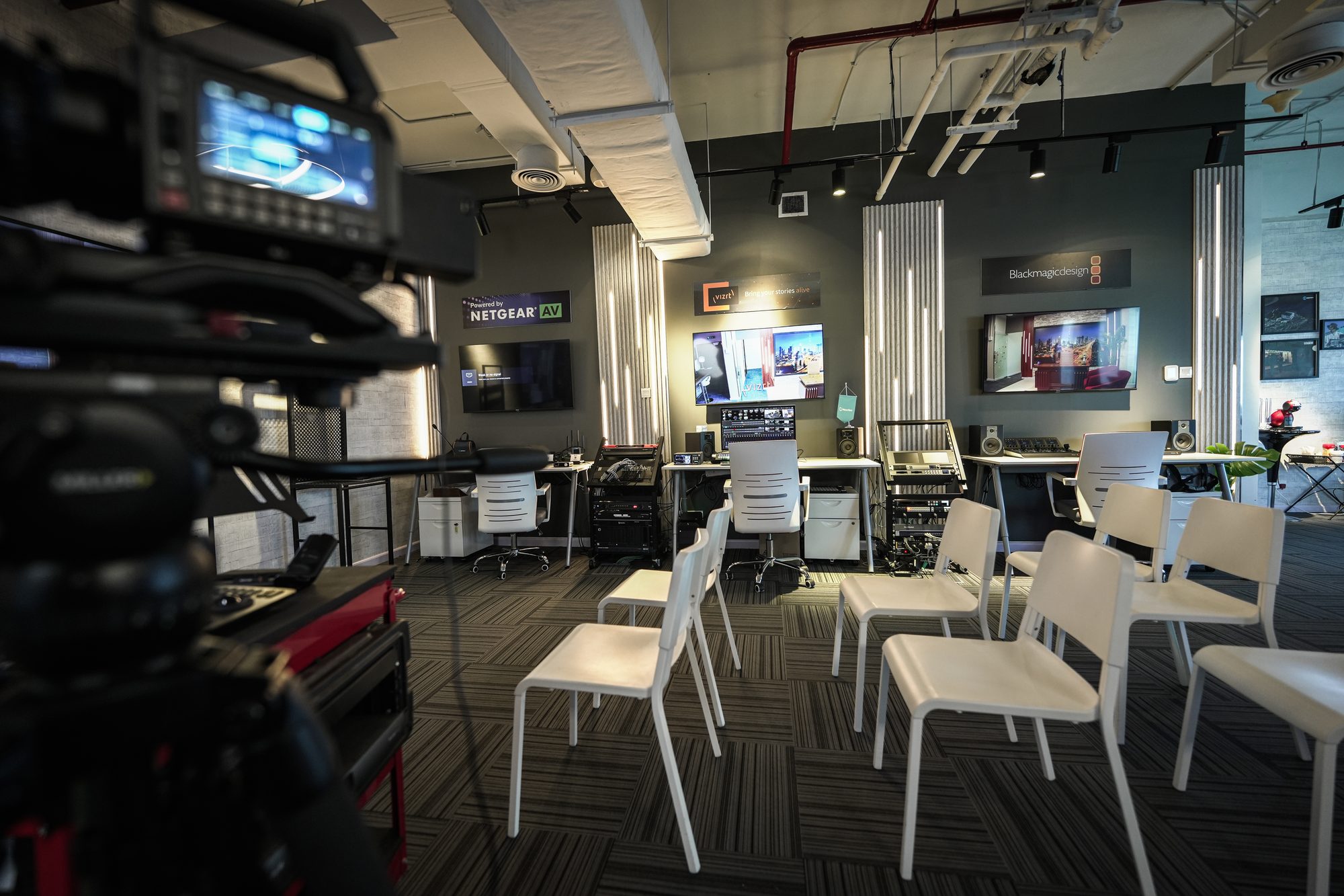 Seating set out for a session, a studio camera and monitor in the foreground