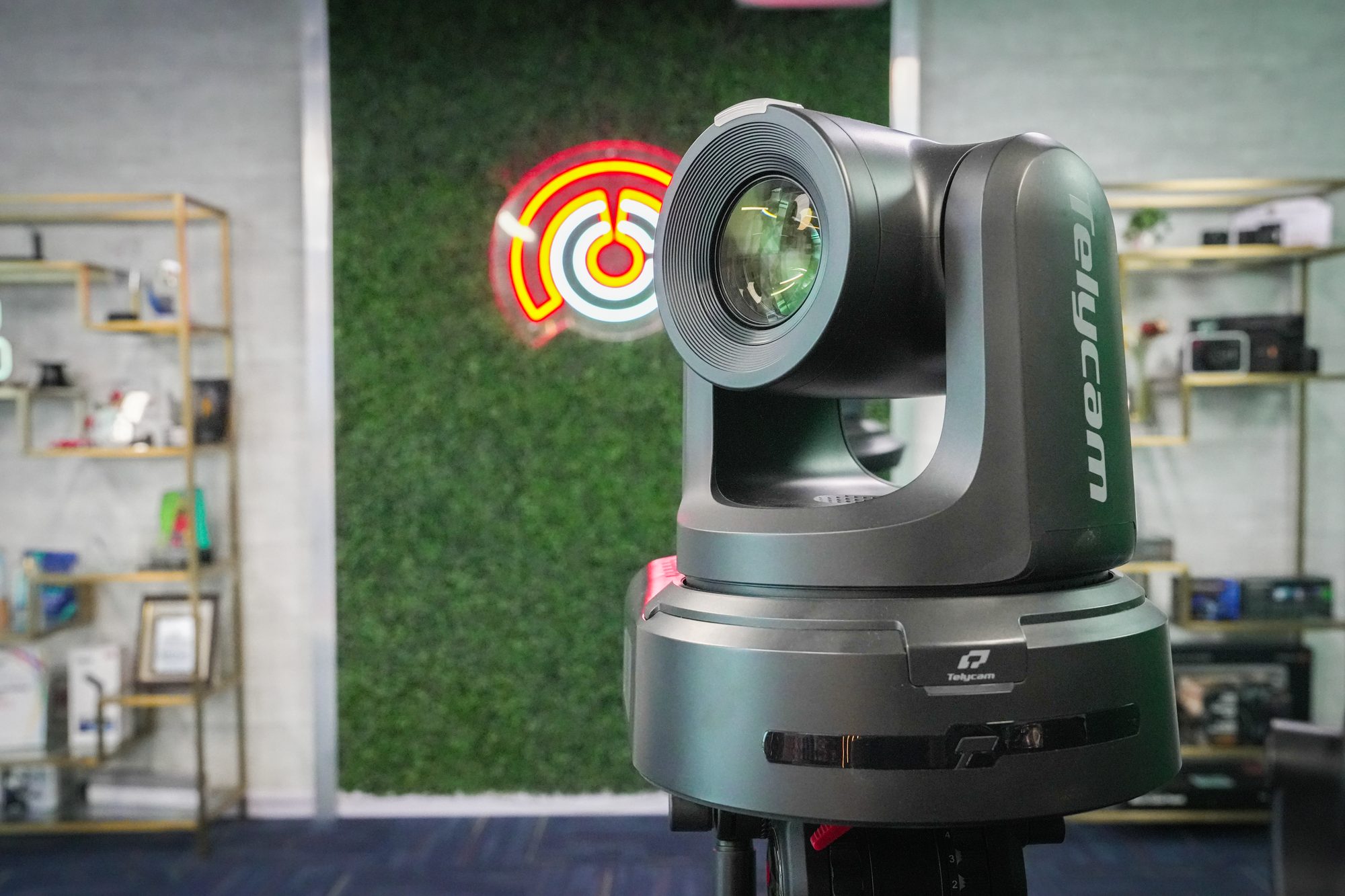 A PTZ camera on the MCX floor beside the neon sign